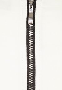 Tissu blanc avec une fermeture éclair noire contrastante courant verticalement, dotée de dents en métal et d'un tirette métallique brillant.