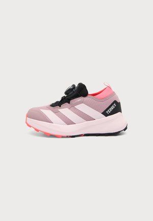 Chaussure de course Adidas Terrex rose et noire avec des bandes blanches, une semelle amortissante et un système de fermeture à molette.
