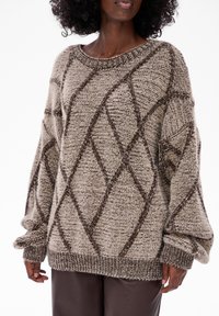 Gruby sweter robiony na drutach w odcieniu beżowym z brązowym wzorem w romby. Posiada szeroki dekolt oraz oversize'owe rękawy z prążkowanymi mankietami.