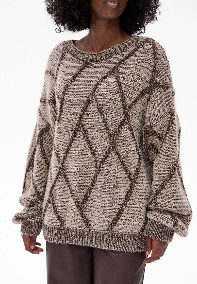 Gruby sweter robiony na drutach w odcieniu beżowym z brązowym wzorem w romby. Posiada szeroki dekolt oraz oversize'owe rękawy z prążkowanymi mankietami.