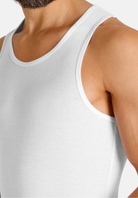 Witte geribbelde tanktop met een ronde halslijn en brede schouderbanden, die een gladde, aansluitende pasvorm en zachte textuur toont.