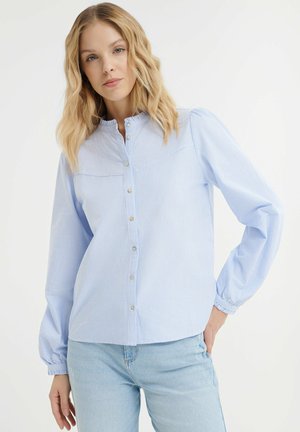 Lichtblauwe gestreepte blouse met een gerimpelde kraag, lange pofmouwen en een rechte zoom. Kleine, parelachtige knopen aan de voorkant.