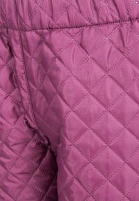 Quiltet lyserødt stof med diamantformet syning. Materialet har en glat, skinnende tekstur. Elastisk talje synlig øverst.