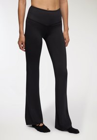Czarne legginsy z rozszerzaną nogawką wykonane z elastycznego materiału; wysoki pas i gładka faktura. Charakteryzują się dopasowanym krojem, który rozszerza się od kolan w dół.