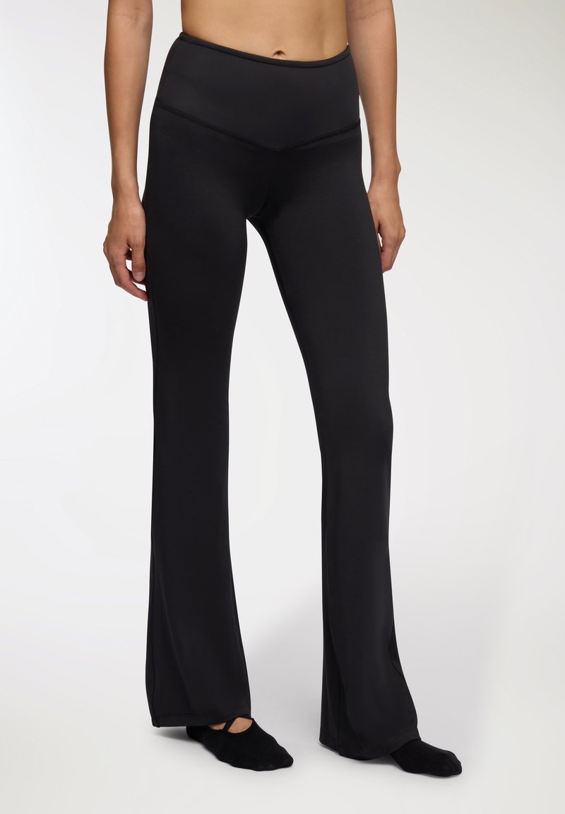 Czarne legginsy z rozszerzaną nogawką wykonane z elastycznego materiału; wysoki pas i gładka faktura. Charakteryzują się dopasowanym krojem, który rozszerza się od kolan w dół.