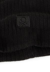 Czarna dziana czapka typu beanie o prążkowanej strukturze. Z przodu małą czarną metkę materiałową z logo. Wykonana z miękkiego i ciepłego materiału.
