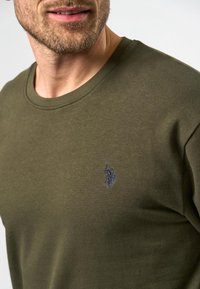 Olijfgroene katoenen crew neck t-shirt met een subtiele marineblauwe geborduurde logo op de borst, een gladde textuur en een standaard pasvorm.