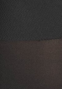 Tissu noir à motifs avec une surface lisse et texturée. Divisé en deux nuances : le haut est entièrement noir et le bas est un marron plus sombre, légèrement translucide.