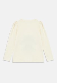 Camicia crema a maniche lunghe in morbido cotone, con spalle arricciate e scollo rotondo. Retro semplice senza ulteriori decorazioni.