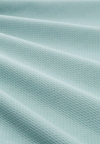 Hellblaues Textil mit einer strukturierten Oberfläche und einem gewebten Muster, das feine Rippungen und eine weiche, atmungsaktive Haptik zeigt. Ideal für verschiedene Anwendungen.
