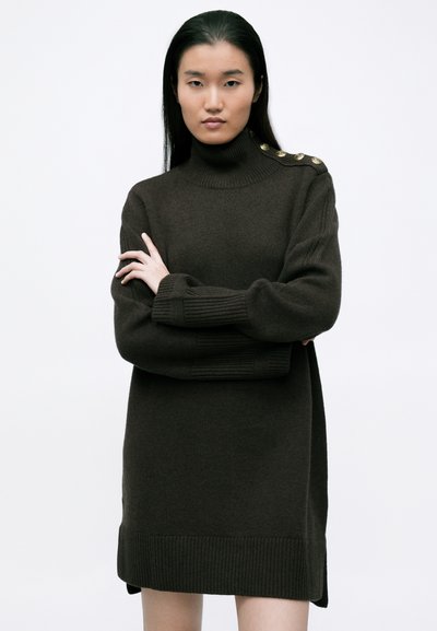 Σκούρο καφέ πλεκτό φόρεμα με ψηλό γιακά, διακοσμημένο με χρυσά κουμπιά στους ώμους. Έχει ριμπ γύρους και στρίφωμα με πλαϊνές σχισμές.