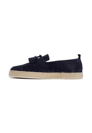 Espadrilla slip-on in camoscio blu navy con suola in corda beige e nappine decorative, vista laterale su sfondo bianco.