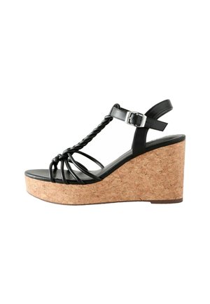 Schwarze Plattform-Sandale mit Kork-Blockabsatz, ausgestattet mit geflochtenen Riemen und verstellbarem Knöchelriemen. Glatte Textur und offenes Zehendesign.
