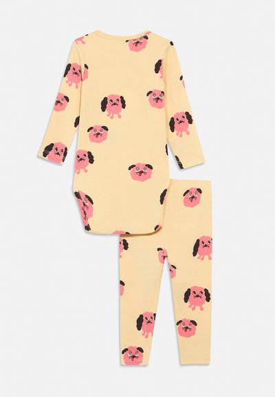 Sárga hosszú ujjú pizsama, hozzá illő nadrággal, amelyen rózsaszín rajzfilm kutyafejek fekete fülekkel ismétlődő mintázatban szerepelnek.