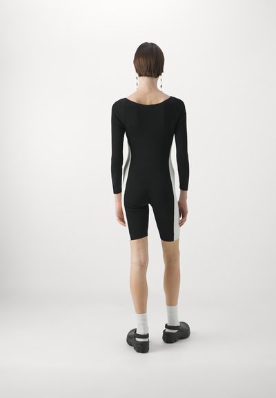 Musta bodysuit pikkade varrukatega, valgete külgpaneelidega, keha järgi vormitud ja ümarate kaelustega. Kanda sokkide ja paksude kingadega.