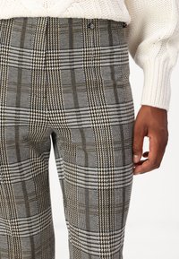 Graue Karohosen mit einem Mix aus Hundegebiss- und Karo-Mustern, verziert mit Nuancen von Beige und Braun. Passt hervorragend zu einem strukturierten Strickoberteil.
