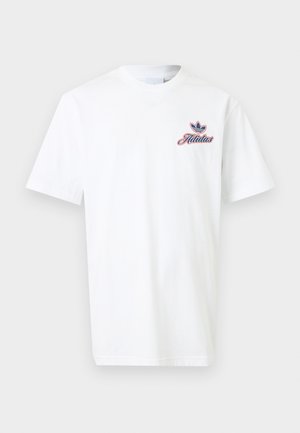 Camiseta blanca de manga corta con pequeño logo de Adidas en azul y rojo en el lado superior izquierdo del pecho, fondo liso.