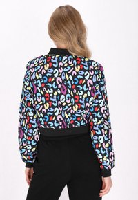 Giacca bomber cropped con fantasia leopardata colorata su base nera; presenta polsi e orlo a costine, realizzata in tessuto morbido.