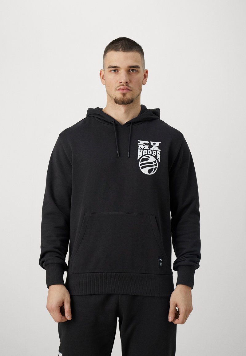 Sudadera negra con capucha, que presenta un logo blanco de "PUMA HOOPS" y una gráfica de baloncesto en el pecho. Incluye un bolsillo delantero y puños de canalé.
