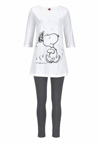 White tunic top with black Snoopy graphic and stars, paired with dark gray leggings. Features a rounded neckline and three-quarter sleeves.