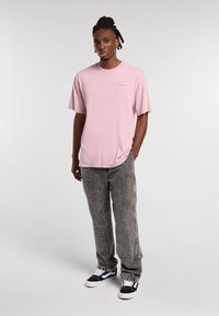 Rosa bomull T-shirt med korta ärmar och rund halsringning, i kombination med blekta grå jeans och svart-vita sneakers.