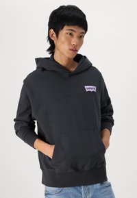 Sudadera con capucha de color gris oscuro, con un bolsillo frontal tipo canguro y el logo de Levi's en púrpura en el lado izquierdo del pecho; fabricada con un tejido suave y texturizado.