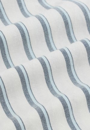 Bela tkanina z enakomerno razporejenimi navpičnimi modrimi in črnimi črtami, prikazana v nežnih gubah, ki izpostavljajo teksturo in vzorec.
