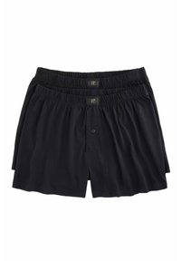 Shorts en coton noirs avec taille élastique et fermeture à bouton, présentés dans un arrangement en pile.