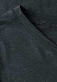 Tessuto di maglietta grigio scuro con una texture liscia, caratterizzato da una scollatura a V e cuciture a contrasto. Motivi sottili creano un aspetto raffinato.