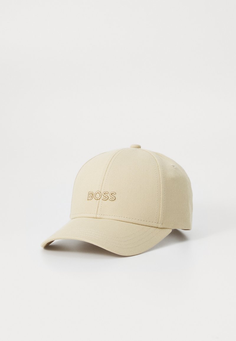 Beige baseball cap laget av stoff, med en buet skjerm og brodert "BOSS"-logo på forsiden. Glatt tekstur og rund krone.