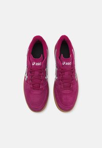 Zapatillas de ante fucsia con acentos en negro, logo blanco y suela de goma. Presentan un diseño con cordones y área del dedo perforada para mayor transpirabilidad.