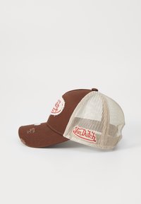 Gorra marrón con visera curva, parte trasera de malla y parche de logotipo rojo. Presenta acentos desgastados en la parte delantera y lateral.