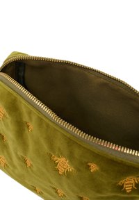 Oliwkowa aksamitna sakiewka z haftem złotej pszczoły, wyposażona w złote metalowe zamknięcie na zamek oraz gładką podszewkę wewnętrzną.