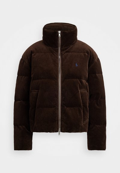 Jachetă puffer din corduroy maro, cu guler înalt, fermoar frontal și detalii cu logo albastru. Prezintă o siluetă pătrată și o textură netedă.