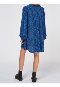 Sininen leopardi-printti mekko pitkillä puffihihnoilla, rento istuvuus ja kerätyt yksityiskohdat olkapäillä. Yhdistetty mustiin nilkkureihin.