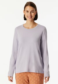 Light purple long-sleeve shirt with a round neckline and smooth texture, paired with patterned orange pants featuring floral designs.