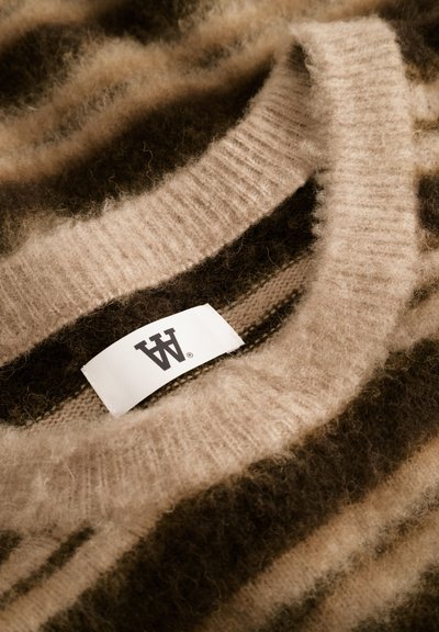 Pull en tricot rayé beige et marron avec une texture douce. Présente un col côtelé et une étiquette d'entretien cousue à l'intérieur.