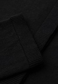 Maglione nero in maglia con dettagli a costine sul colletto e sui polsini. La trama è liscia e morbida, evidenziando un design monocromatico.