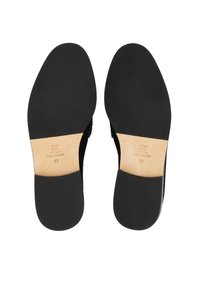 Zapatos de cuero negro con suelas lisas, con una plantilla beige marcada "CUERO REAL" y tamaño "37." Diseño simple y elegante.