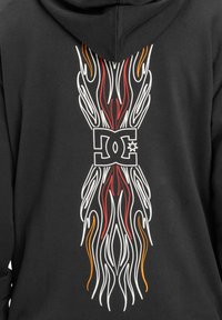 Sudadera negra con un diseño gráfico audaz en la parte posterior que presenta patrones en forma de llamas en blanco, rojo y naranja alrededor de un logo central.