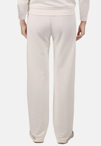 Witte, comfortabele sweatpants met een gladde textuur en een elastische tailleband. Heeft iets taps toelopende benen en minimale stikdetails.