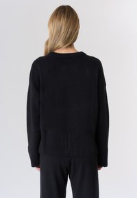 Maglione nero a maglia con orlo e polsini a coste, vestibilità comoda e scollatura arrotondata; texture morbida, design semplice, senza motivi visibili.