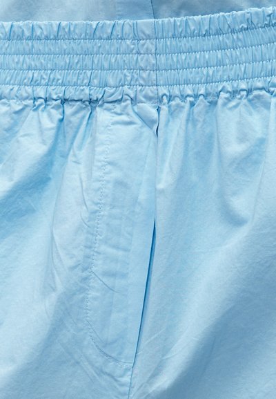 Ανοιχτό μπλε ύφασμα με ελαστική μέση και ραφή στη μέση, που δείχνει μαζετή και λείο υφασμάτινο υφή.