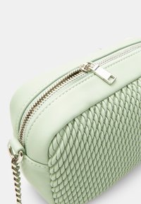 Zöld, szőtt bőr crossbody táska sima felülettel, ezüst cipzárral és lánc pánttal. Téglalap alakú, texturált részletekkel.