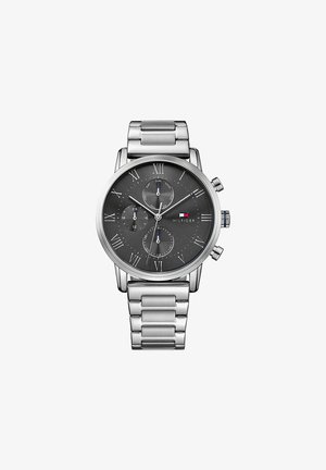 Zilveren roestvrijstalen horloge met een ronde, grijze wijzerplaat, Romeinse cijfers, drie subdialen en een metalen schakelarmband. Beschikt over een kroon aan de zijkant.