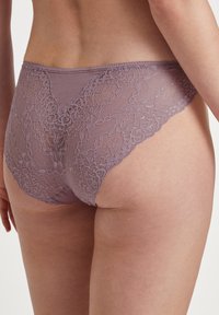 Mutande in pizzo e tessuto elasticizzato color lavanda, con bordo in pizzo floreale e retro liscio, caratterizzate da un delicato bordo a scalloped.