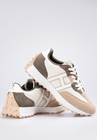 Zapatillas beige y marrón con materiales de malla, ante y goma. Presenta acentos blancos y suela de goma texturizada para mayor tracción.
