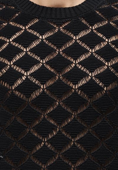 Μαύρο πλεκτό τοπ με μοτίβο διαμαντιού από συμπαγείς και ανοιχτές περιοχές, που αφήνουν να φαίνεται το δέρμα από κάτω, με ριμπ λαιμόκοψη σε στρογγυλό σχήμα.