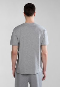 Camiseta de algodón de manga corta en color gris, con cuello redondo y un corte relajado, que presenta un detalle de costura mínima en la parte posterior.