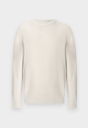 Pull en tricot beige clair avec une surface texturée, encolure ronde et poignets et ourlet côtelés. Design simple et sans embellissements.